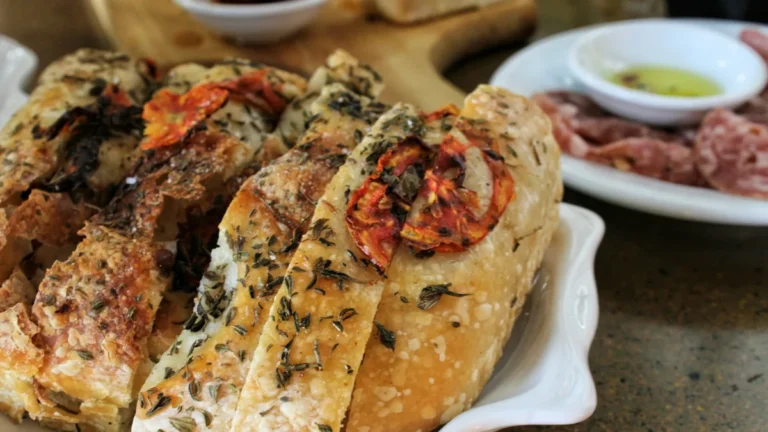 Sliced herb focaccia on a wooden board, ready to eat