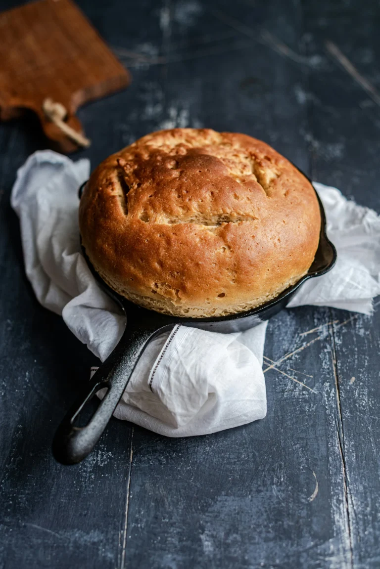 Round sourdough loaf baked in an open skillet, no Dutch oven, with a golden crackled crust