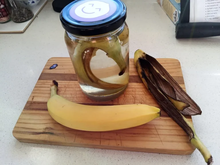 Banana peel fertilizer: a jar of water with a banana peel steeping, beside a whole banana and a spent peel on a wooden board
