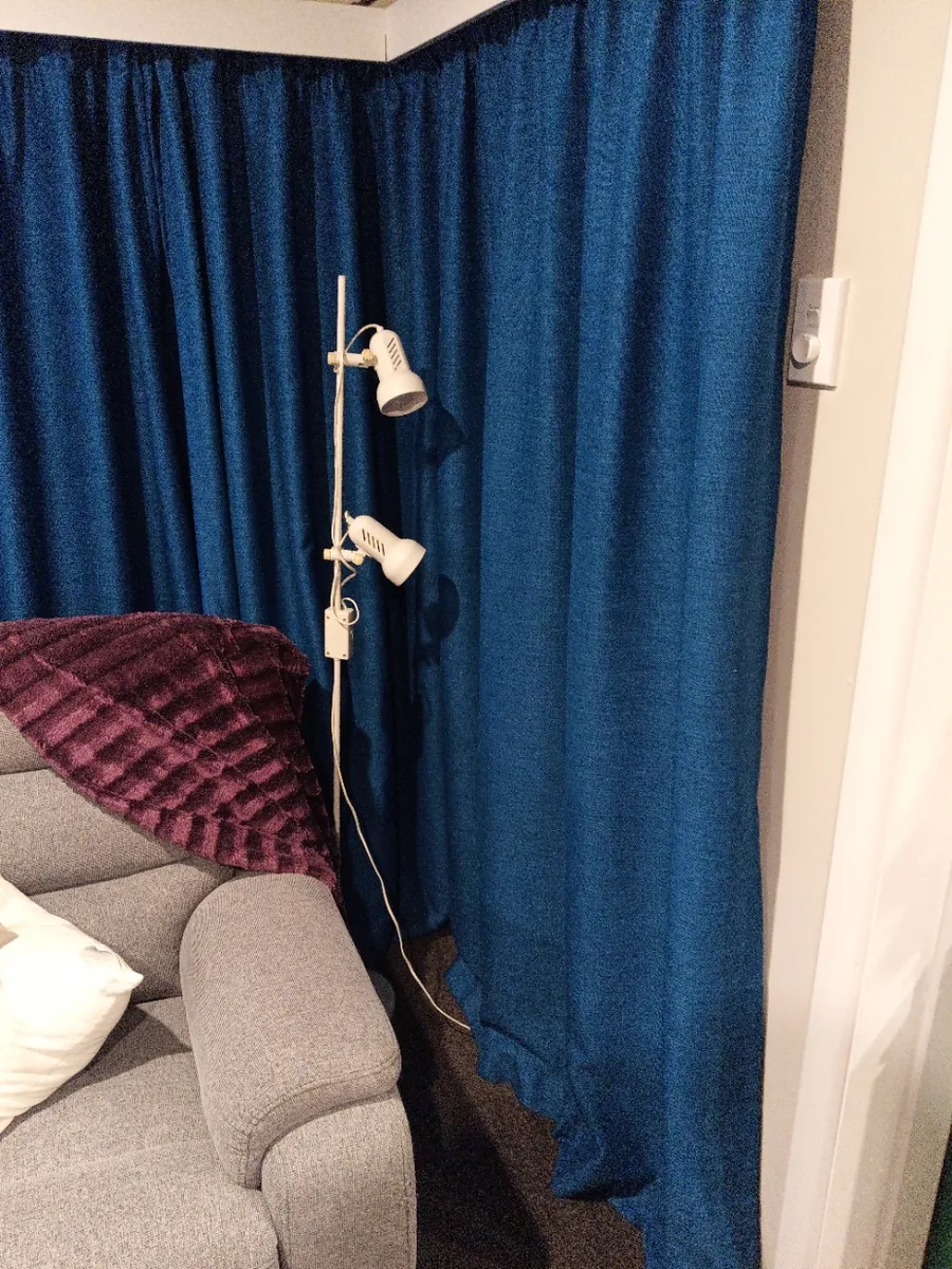 Floor-length blue thermal curtains, closed, hanging from near the ceiling in a living room.