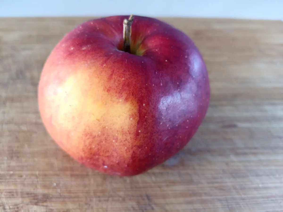 How to dehydrate apples: a whole red apple on a wooden cutting board